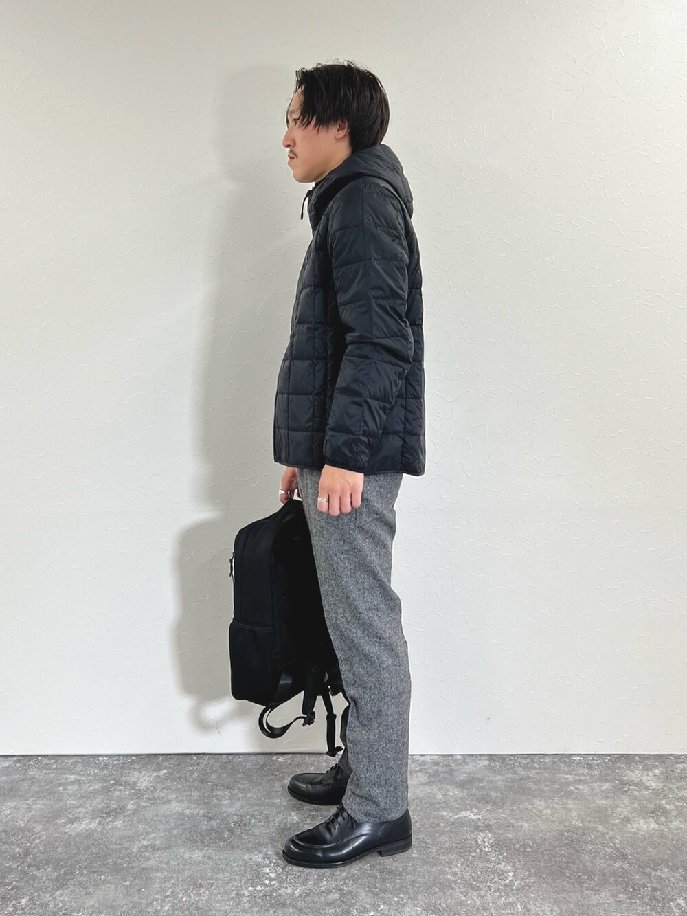 ブラック系のダウンジャケット/コート、レッド系のニット/セーター、グレー系のスラックスを着用したメンズの秋コーディネートの5枚目の写真