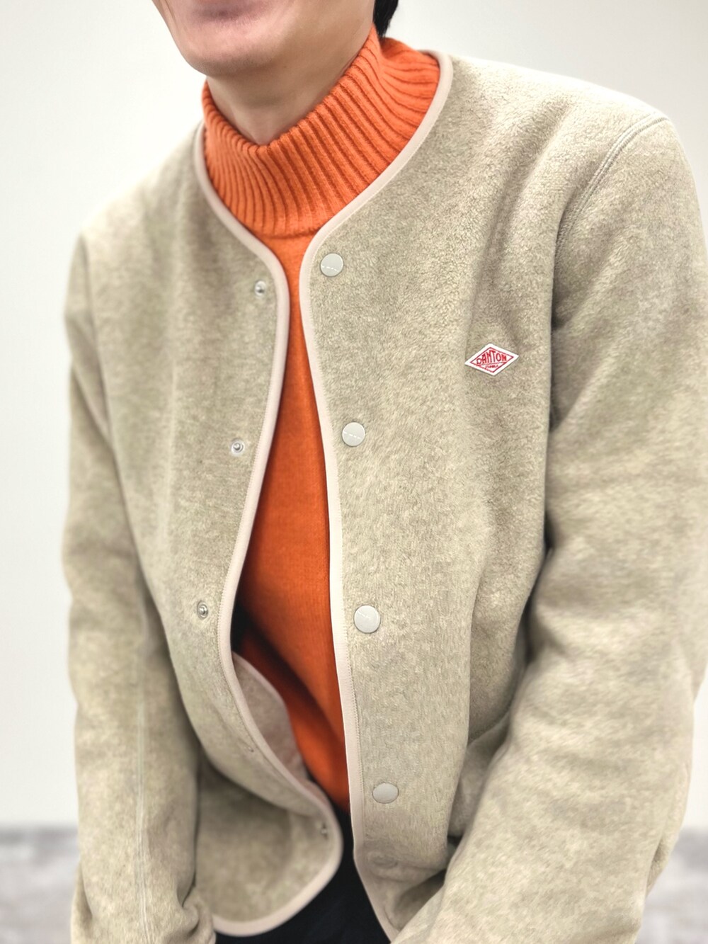 ホワイト系のブルゾン、オレンジ系のニット/セーター、ブラック系のサンダルを着用したメンズの秋コーディネートの6枚目の写真