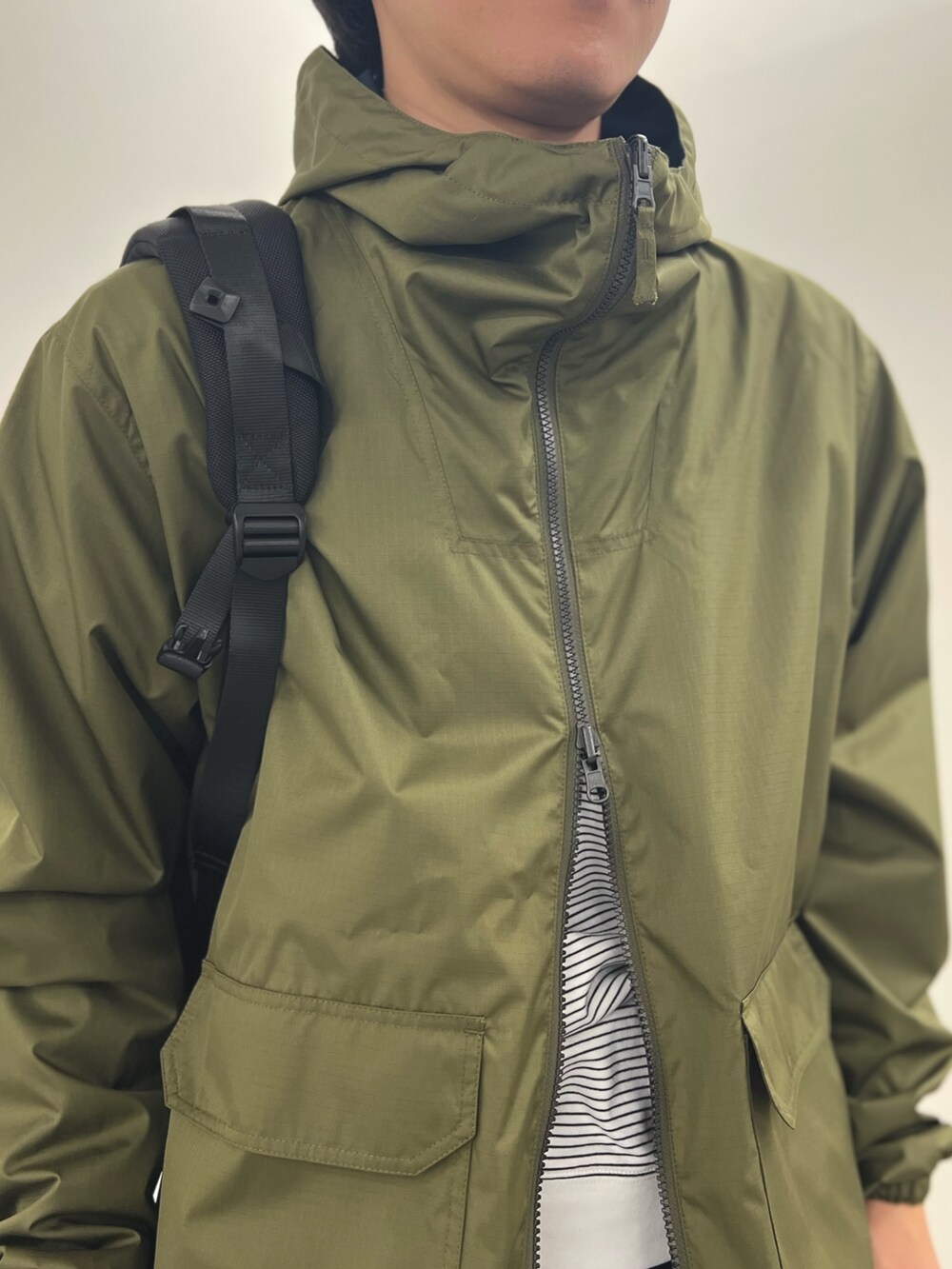 グリーン系のブルゾン、ホワイト系のTシャツ/カットソー、ブルー系のデニムパンツを着用したメンズの冬コーディネートの8枚目の写真