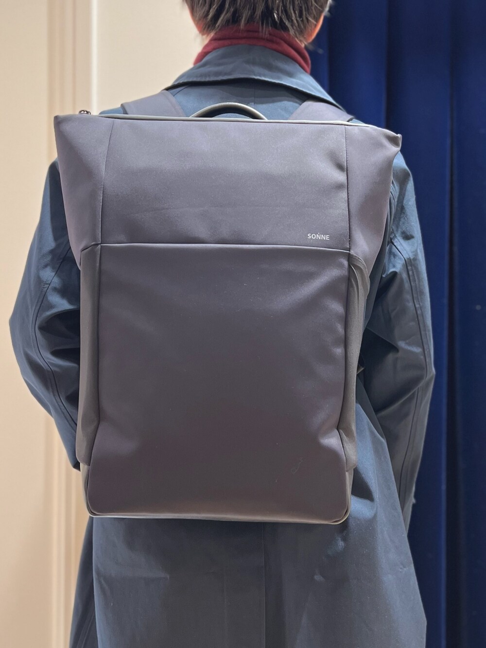 ブルー系のステンカラーコート、ブルー系のその他パンツ、ブラック系のバックパック/リュックを着用したメンズの冬コーディネートの7枚目の写真