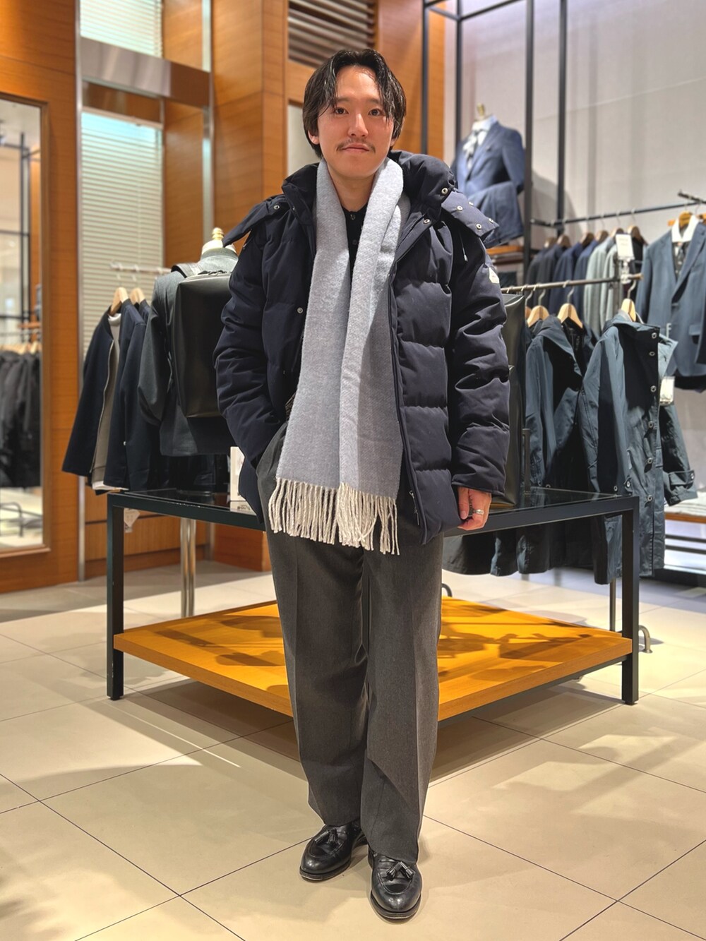 ブルー系のダウンジャケット/コート、ブラック系のトートバッグ、ブラック系のローファーを着用したメンズの冬コーディネートの2枚目の写真