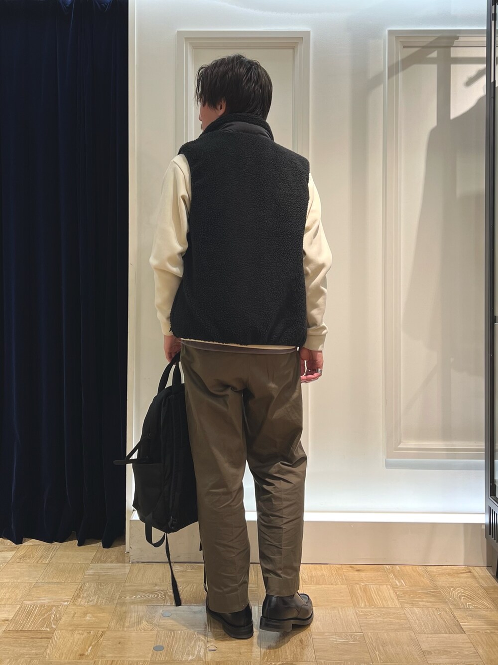 ブラック系のダウンベスト、ホワイト系のTシャツ/カットソー、ブラック系のバックパック/リュックを着用したメンズの秋コーディネートの4枚目の写真