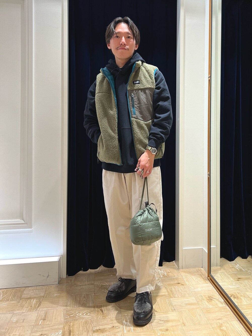 ブラック系のパーカー、グリーン系のダウンベスト、グリーン系のショルダーバッグを着用したメンズの秋コーディネートの2枚目の写真