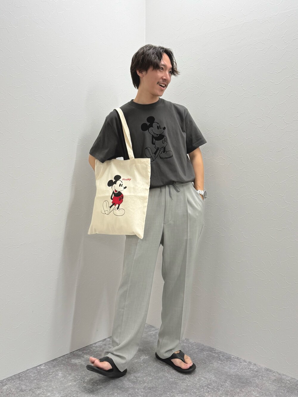 ブラック系のTシャツ/カットソー、ホワイト系のトートバッグ、ブラック系のサンダルを着用したメンズの夏コーディネートの2枚目の写真