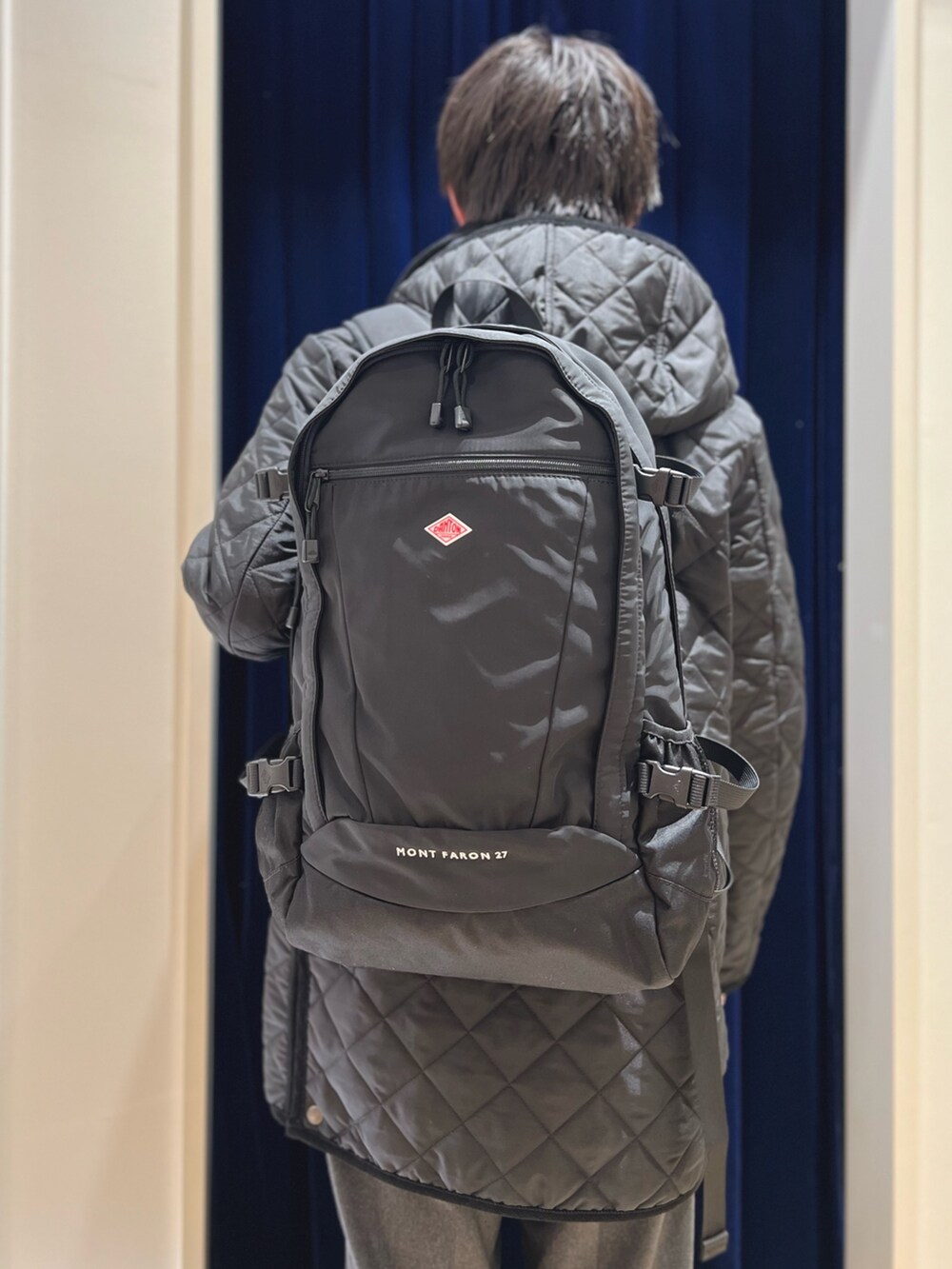 ブラック系のステンカラーコート、ブラック系のローファー、ブラック系のバックパック/リュックを着用したメンズの冬コーディネートの6枚目の写真