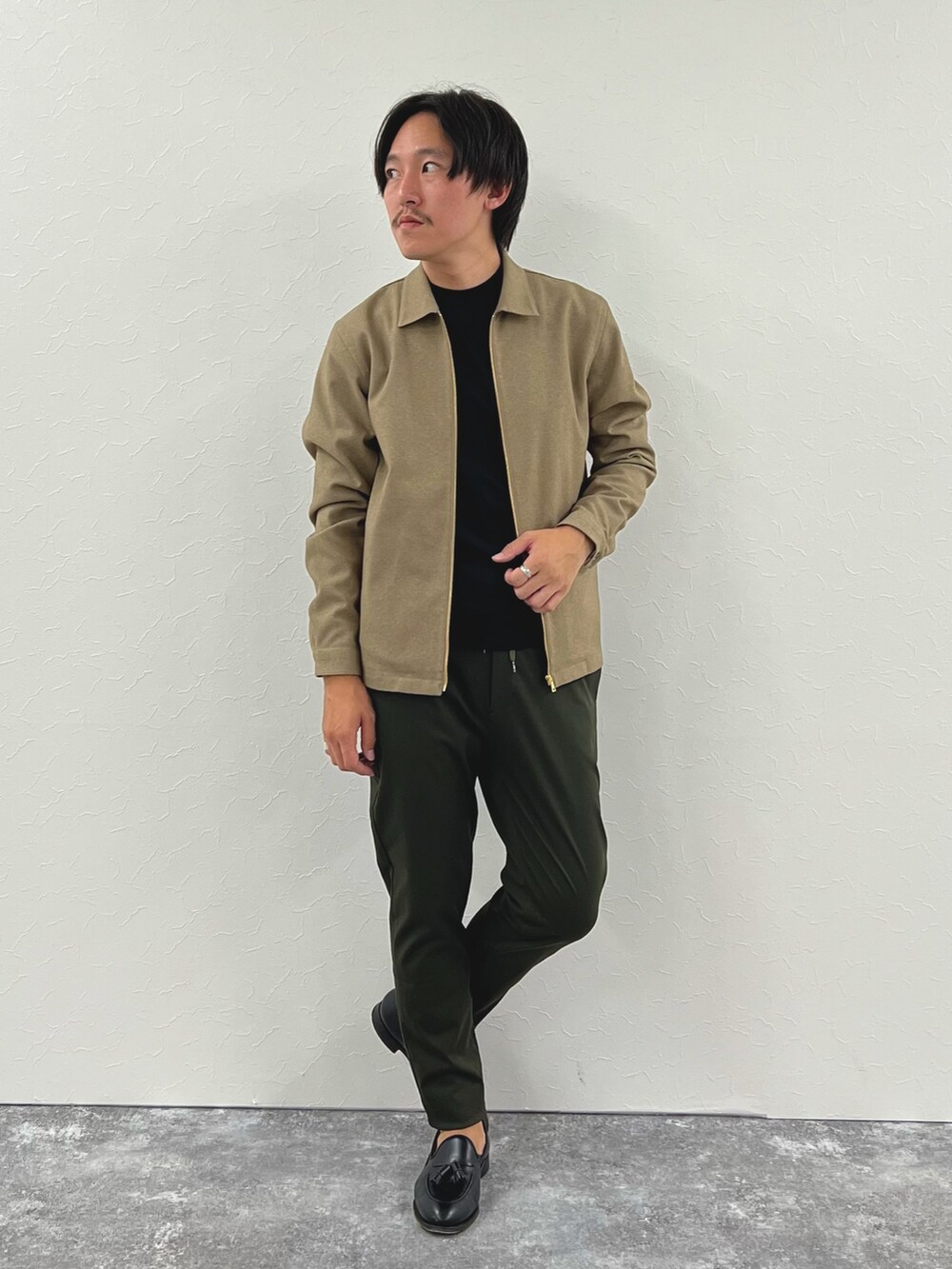 ベージュ系のブルゾン、ブラック系のTシャツ/カットソー、グリーン系のその他パンツを着用したメンズの秋コーディネートの2枚目の写真
