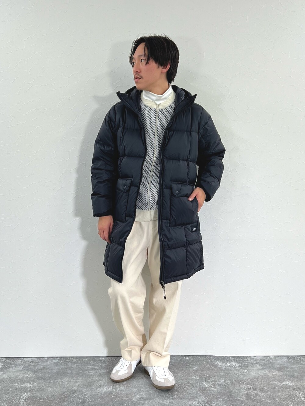 ブラック系のダウンジャケット/コート、ホワイト系のカーディガン/ボレロ、ホワイト系のTシャツ/カットソーを着用したメンズの冬コーディネートの2枚目の写真
