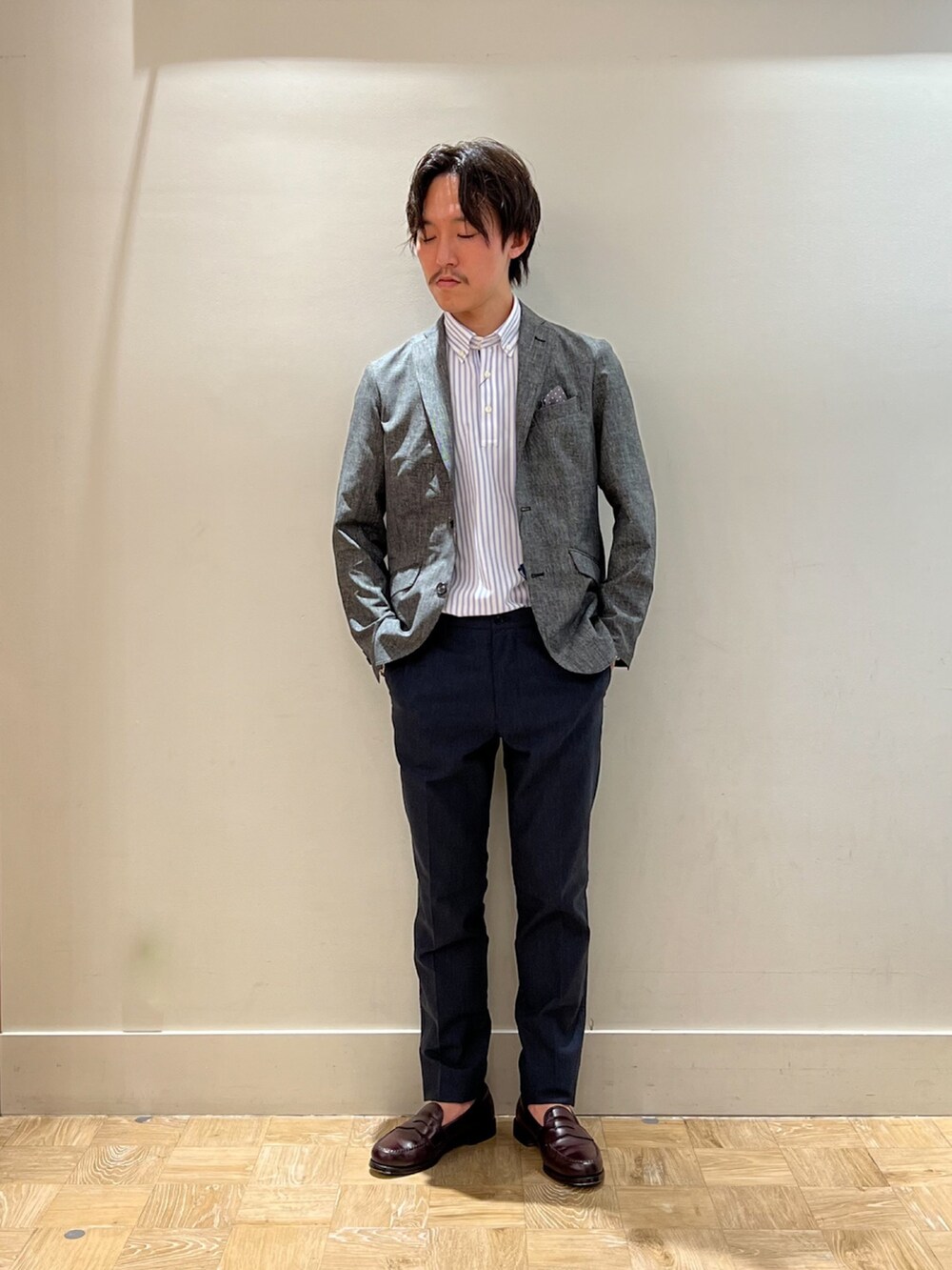 グレー系のテーラードジャケット、ホワイト系のポロシャツ、ブルー系のその他パンツを着用したメンズの夏コーディネートの2枚目の写真