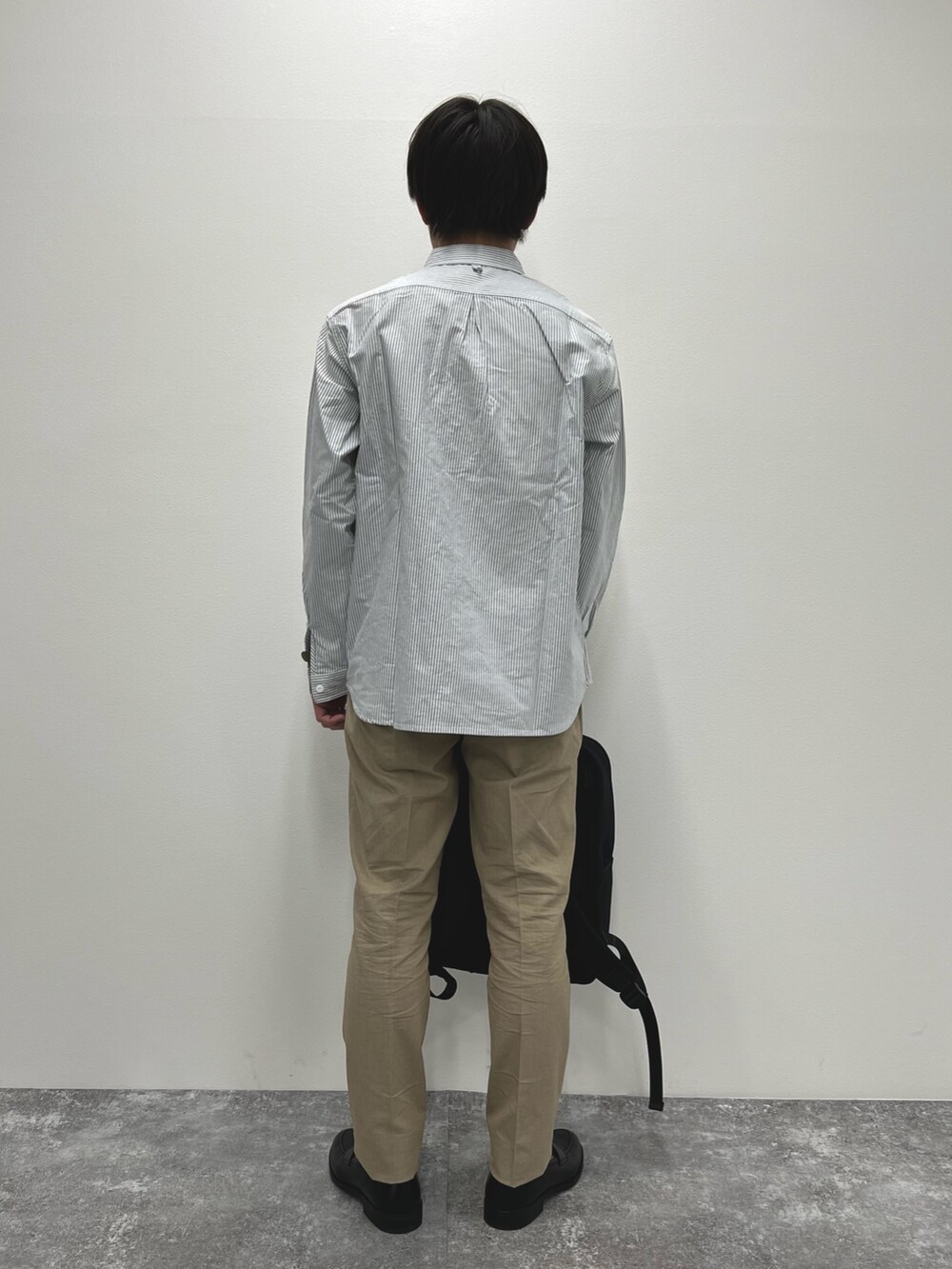 ブラック系のシャツ/ブラウス、ベージュ系のチノパンツ、ブラック系のバックパック/リュックを着用したメンズの春コーディネートの4枚目の写真