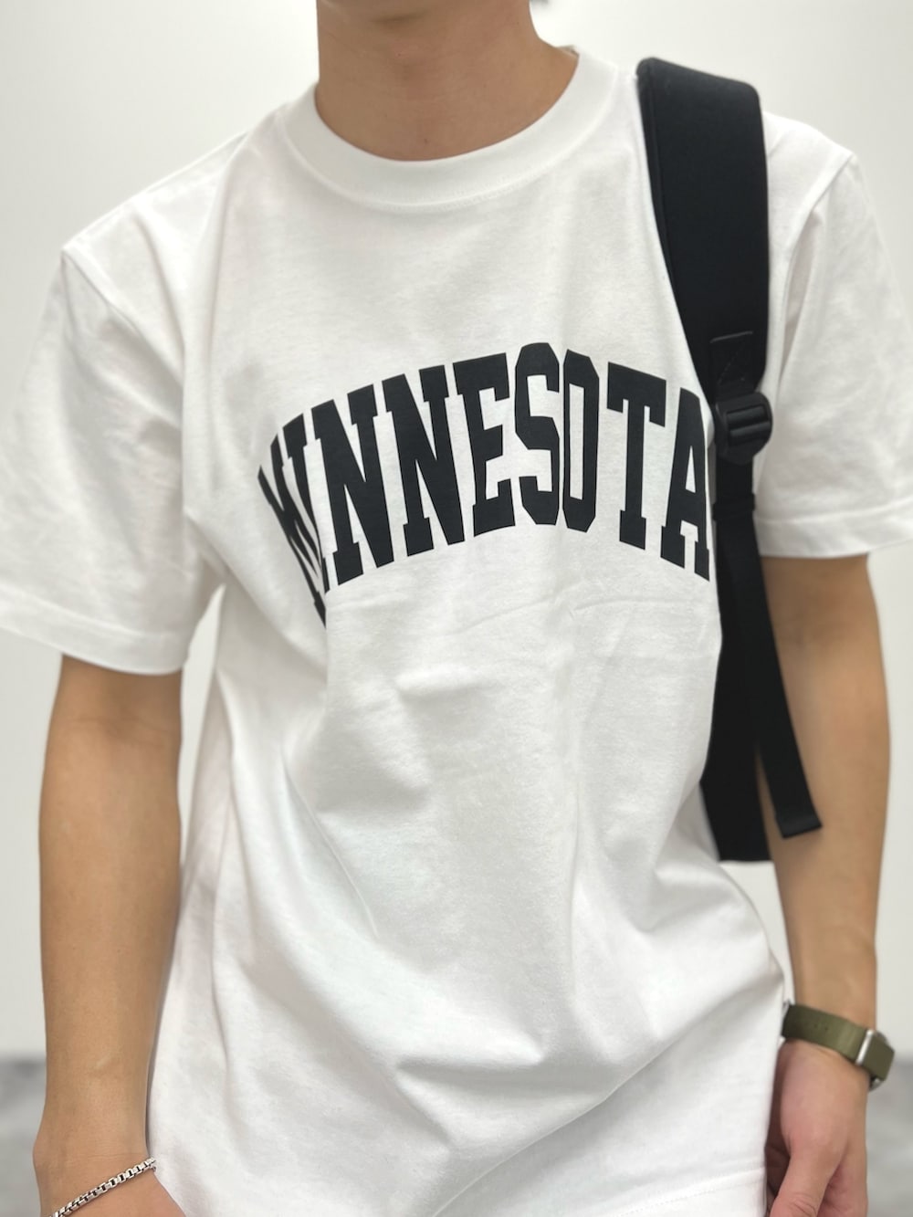 ホワイト系のTシャツ/カットソー、ブラック系のバックパック/リュック、ブラック系のサンダルを着用したメンズの春コーディネートの6枚目の写真