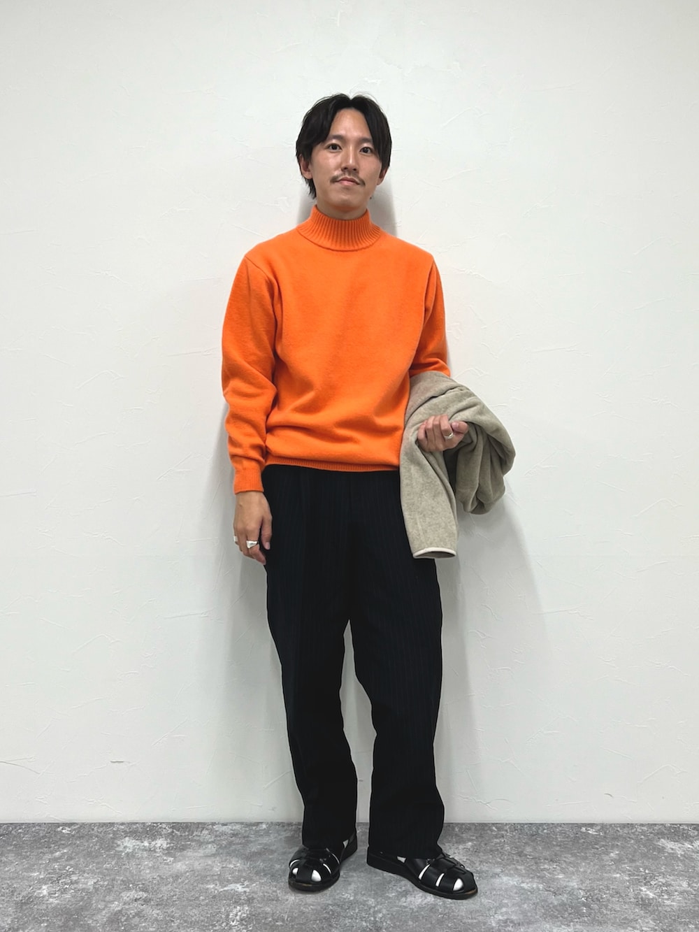 ホワイト系のブルゾン、オレンジ系のニット/セーター、ブラック系のサンダルを着用したメンズの秋コーディネートの3枚目の写真