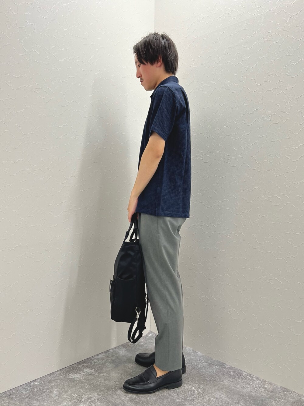 ブルー系のポロシャツ、グレー系のその他パンツ、ブラック系のトートバッグを着用したメンズの夏コーディネートの5枚目の写真