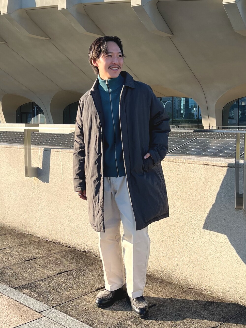 グレー系のダウンジャケット/コート、ブルー系のニット/セーター、ブラック系のその他シューズを着用したメンズの秋コーディネートの2枚目の写真