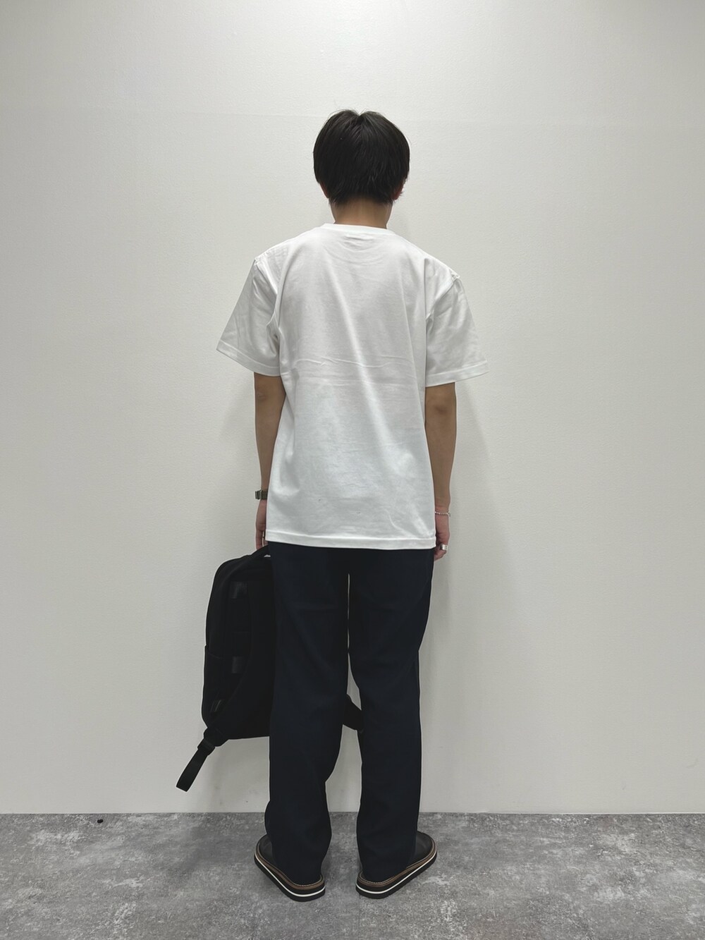 ホワイト系のTシャツ/カットソー、ブラック系のバックパック/リュック、ブラック系のサンダルを着用したメンズの春コーディネートの5枚目の写真