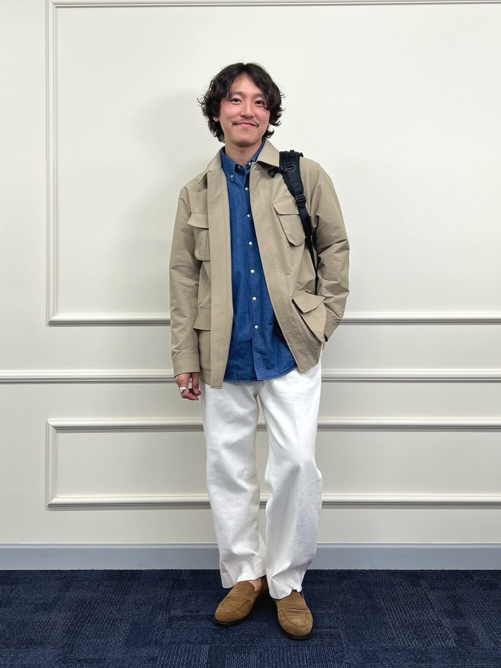 ベージュ系のミリタリージャケット、ブルー系のシャツ/ブラウス、ブラック系のバックパック/リュックを着用したメンズの春コーディネートの2枚目の写真