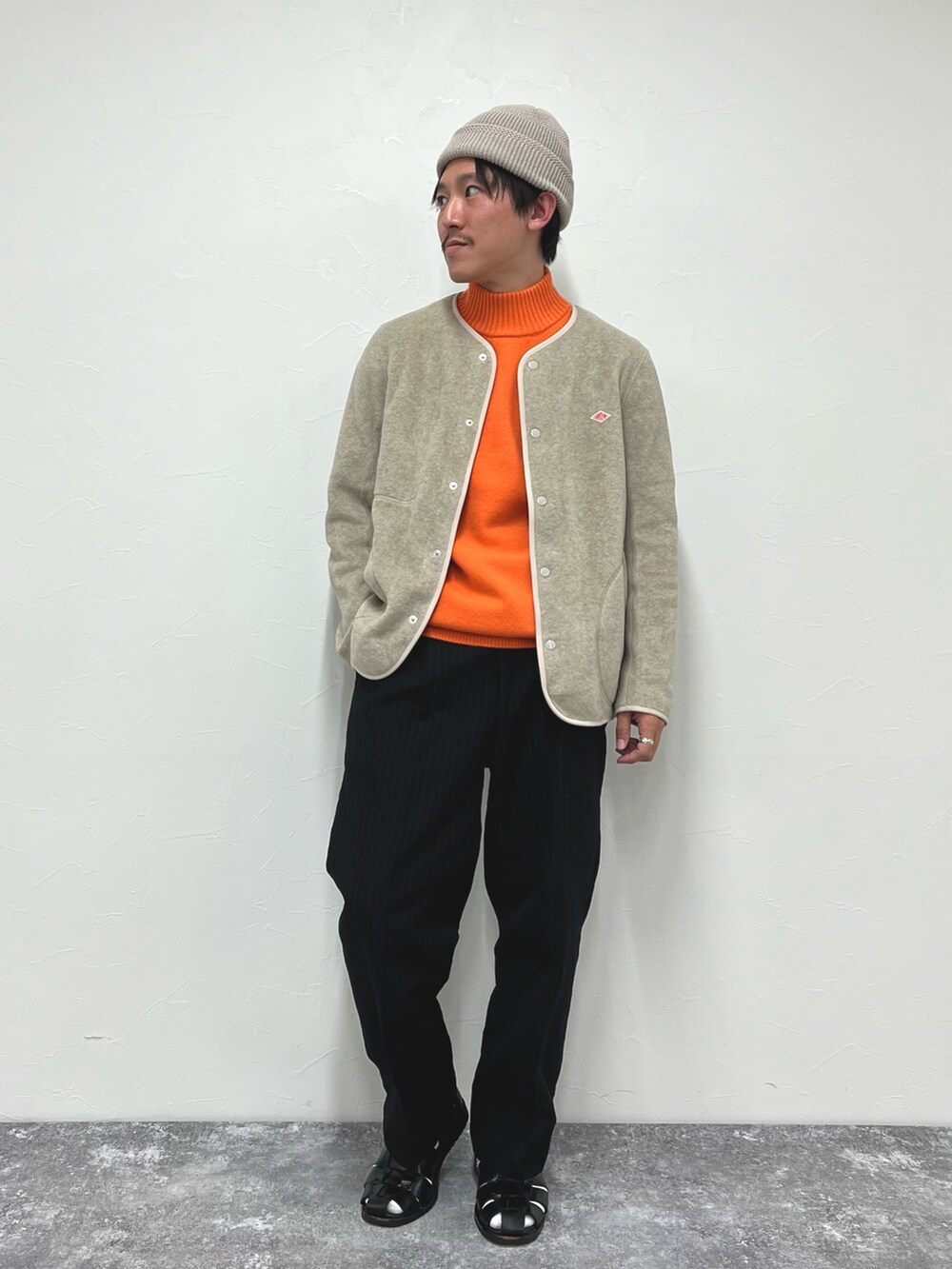 ホワイト系のブルゾン、オレンジ系のニット/セーター、ブラック系のサンダルを着用したメンズの秋コーディネートの2枚目の写真