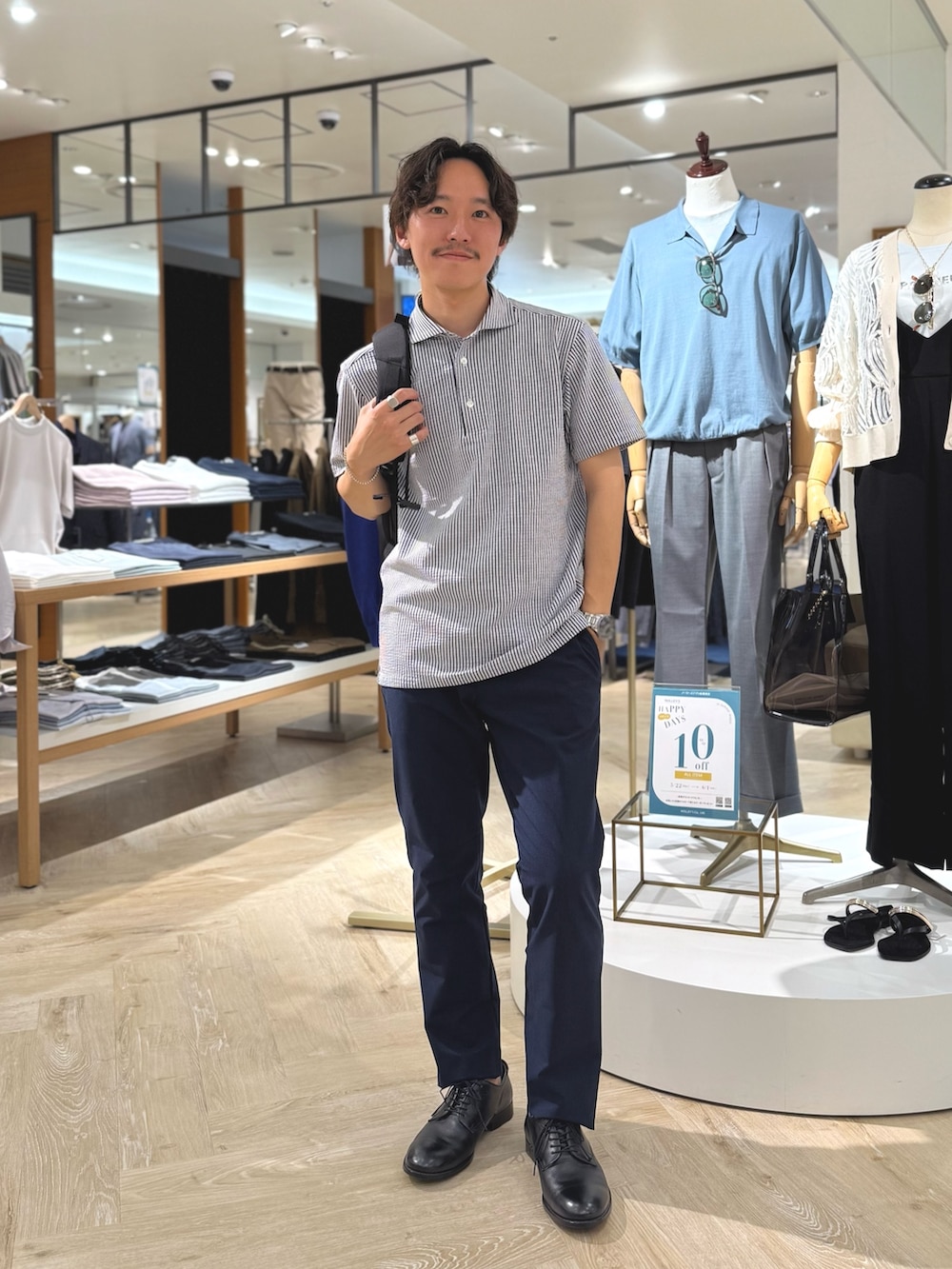 ブルー系のポロシャツ、ブルー系のその他パンツ、ブラック系のバックパック/リュックを着用したメンズの夏コーディネートの2枚目の写真