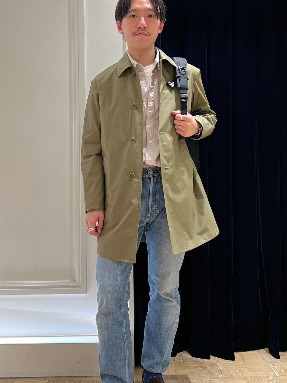 ベージュ系のシャツ/ブラウス、グリーン系のステンカラーコート、ブラック系のバックパック/リュックを着用したメンズの冬コーディネートの2枚目の写真