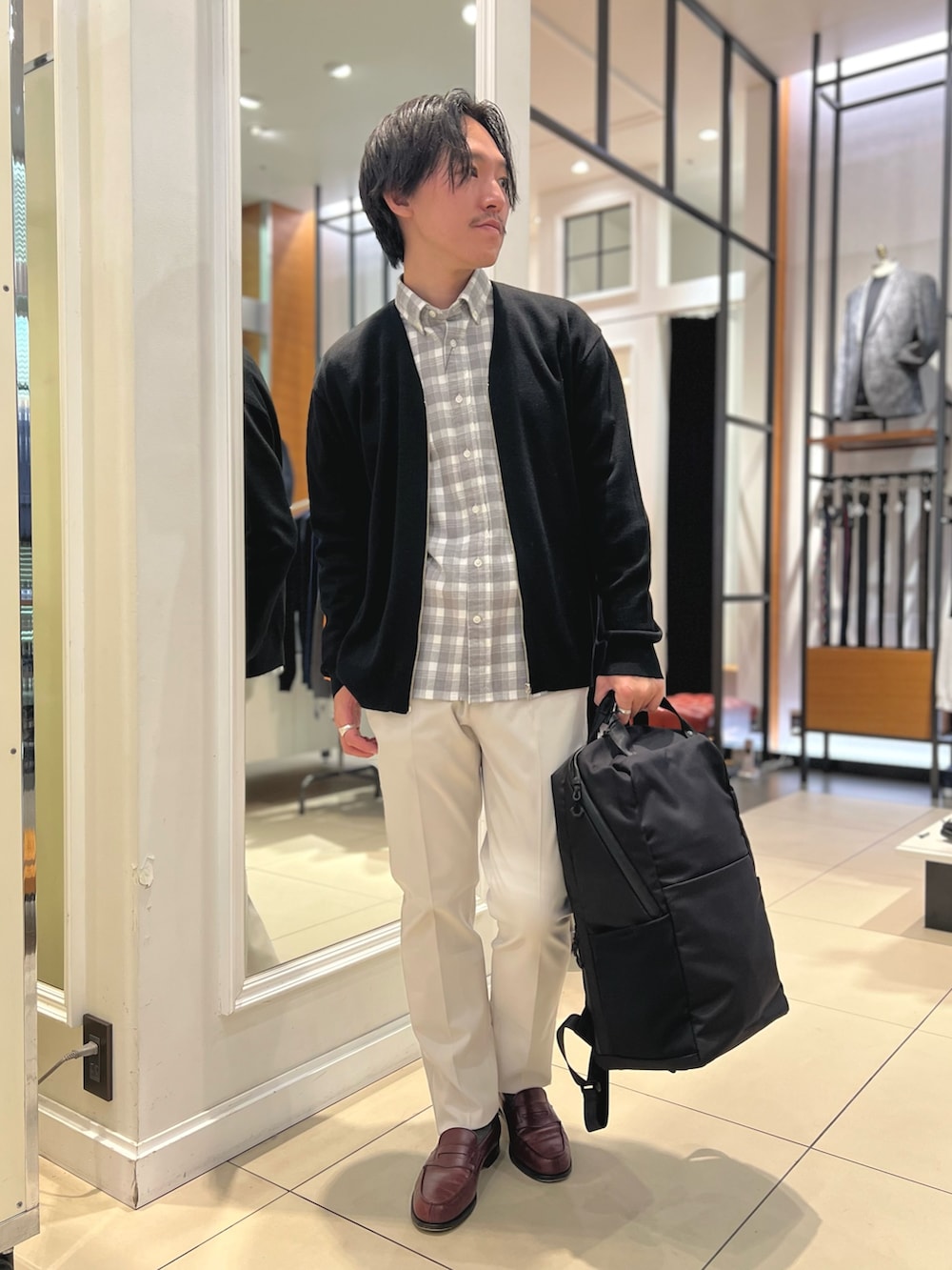 ブラック系のカーディガン/ボレロ、ブラック系のバックパック/リュック、ホワイト系のチノパンツを着用したメンズの冬コーディネートの2枚目の写真