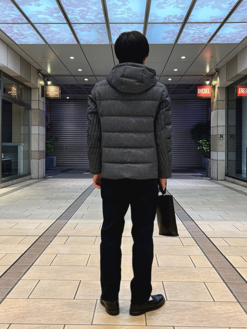 ブルー系のダウンジャケット/コート、ブルー系のニット/セーター、ブルー系のチノパンツを着用したメンズの秋コーディネートの5枚目の写真