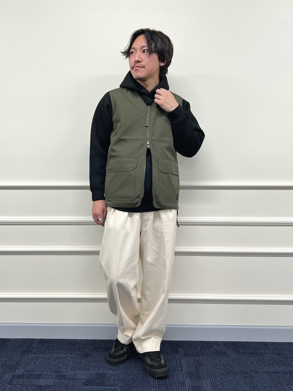 グリーン系のベスト、ブラック系のパーカー、ホワイト系のデニムパンツを着用したメンズの冬コーディネートの5枚目の写真