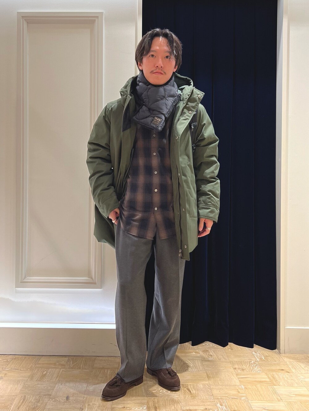 グリーン系のシャツ/ブラウス、ブラック系のバックパック/リュック、グリーン系のダウンジャケット/コートを着用したメンズの冬コーディネートの3枚目の写真