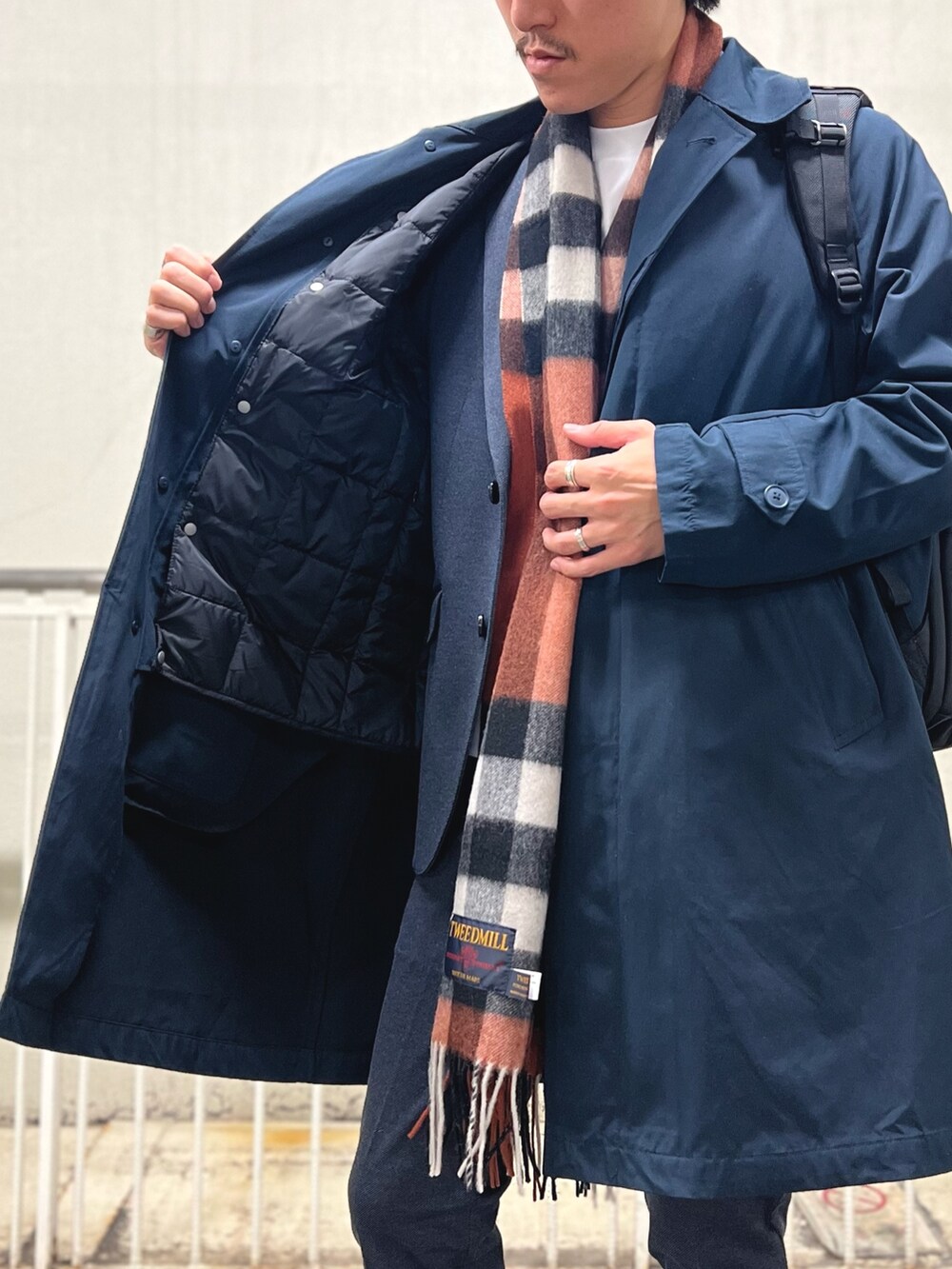 ブラック系のバックパック/リュック、ホワイト系のTシャツ/カットソー、ブルー系のステンカラーコートを着用したメンズの秋コーディネートの8枚目の写真