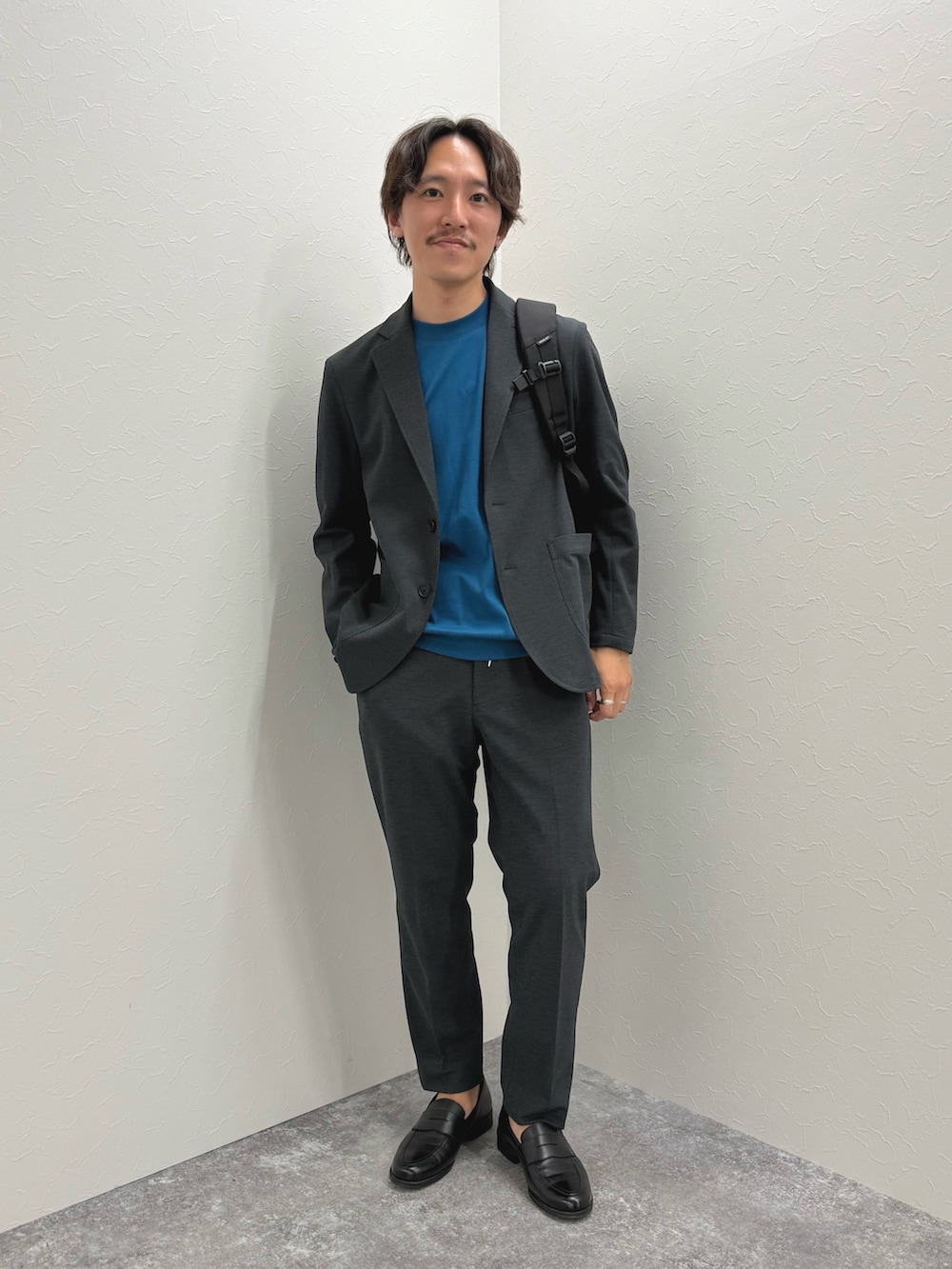 ブラック系のバックパック/リュック、ブラック系のローファー、ブルー系のTシャツ/カットソーを着用したメンズの夏コーディネートの3枚目の写真