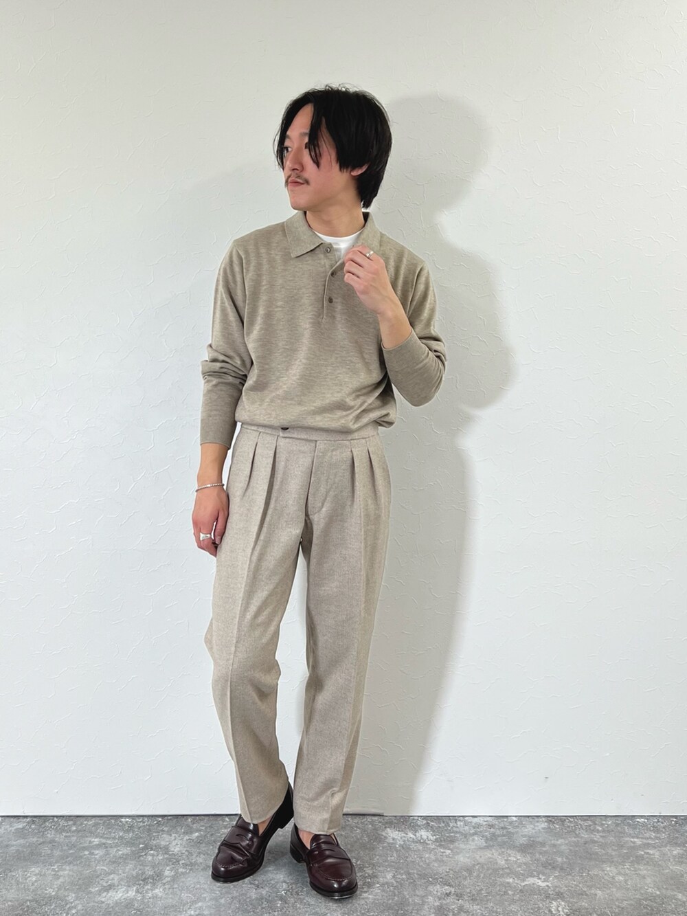 ベージュ系のスラックス、ブラウン系のローファー、ベージュ系のニット/セーターを着用したメンズの冬コーディネートの2枚目の写真