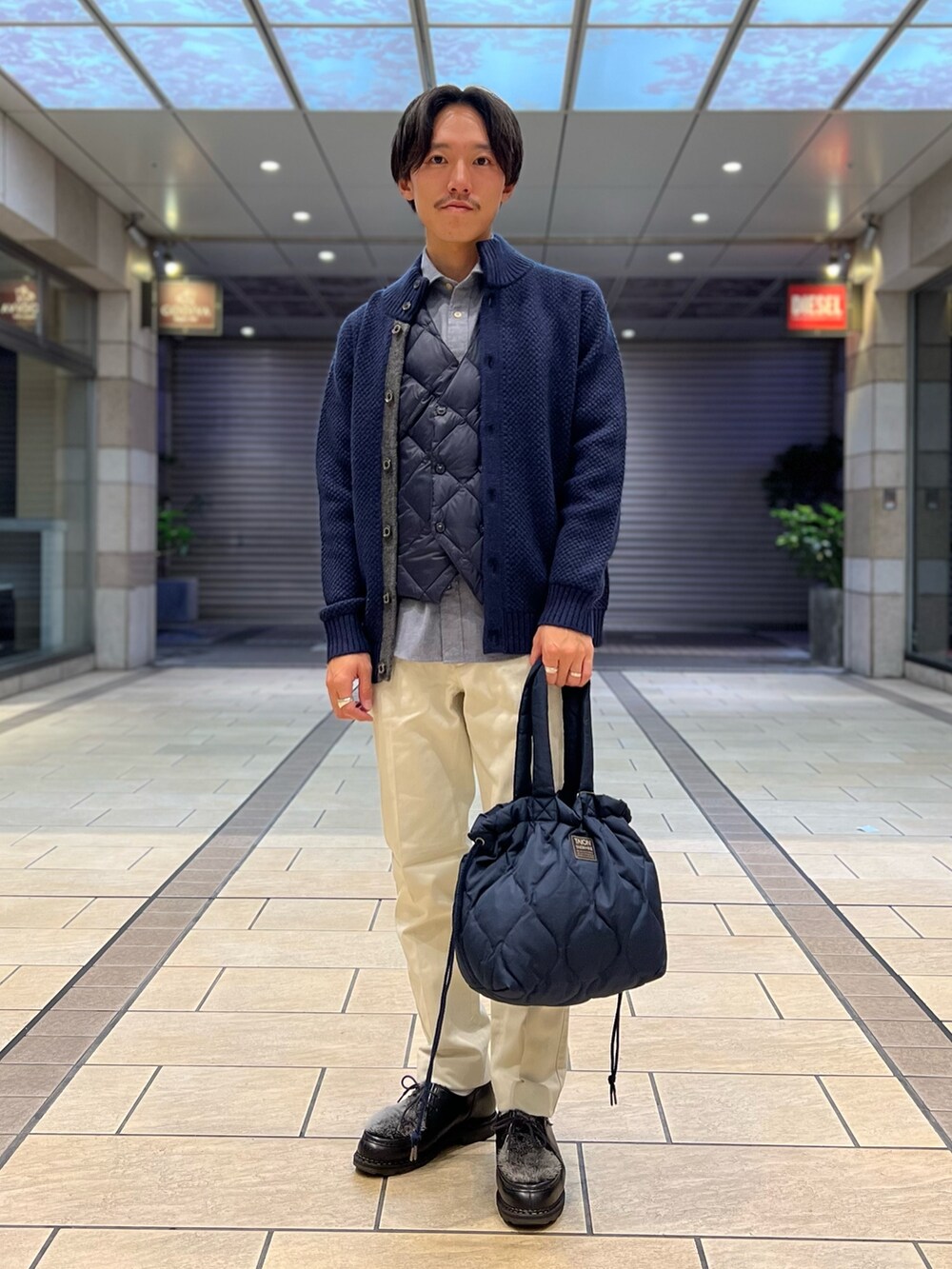 「ファッションを楽しもう、レイヤードスタイル、お出かけコーデ、きれいめカジュアル、トートバッグ、ローファー、ニット、カジュアルコーデ、休日コーデ、秋冬コーデ、冬コーデ、ダウン、ダウンベスト、カーディガン」|「TAIONの【TAION/タイオン】MILITARY DOWN TOTE BAG M(トートバッグ、ブルー系)」を使った、nishiokaさん(メンズ・169cm)の秋コーディネートの2枚目の写真