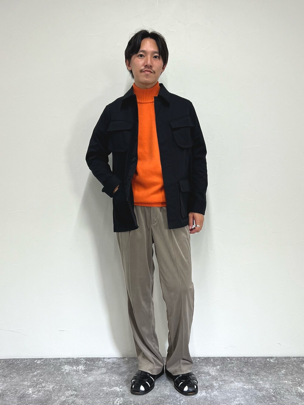 オレンジ系のニット/セーター、ブラック系のミリタリージャケット、ベージュ系のその他パンツを着用したメンズの秋コーディネートの4枚目の写真
