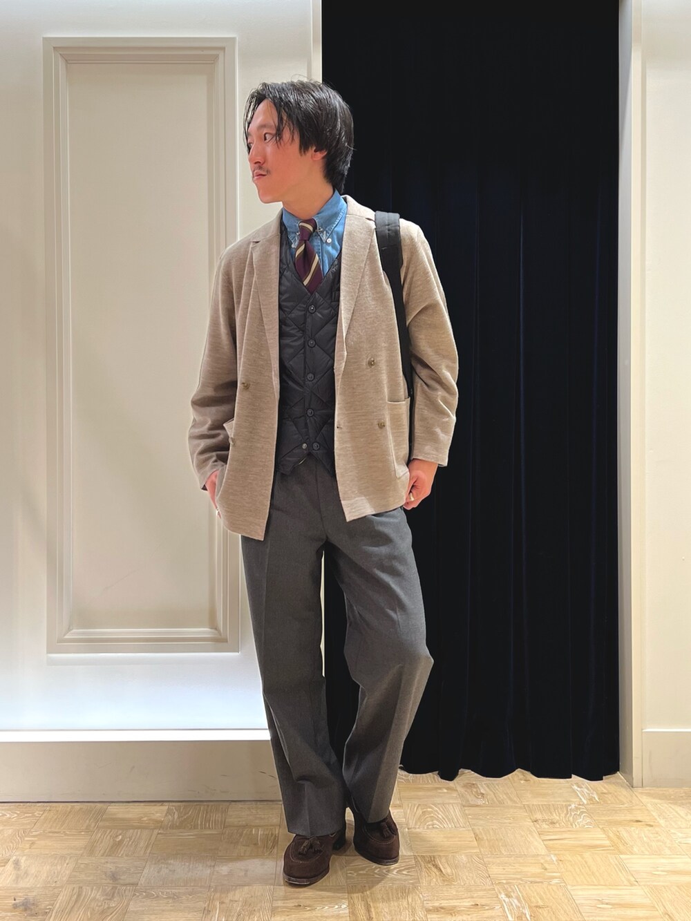 ベージュ系のテーラードジャケット、ブラック系のダウンベスト、ブラック系のバックパック/リュックを着用したメンズの冬コーディネートの4枚目の写真