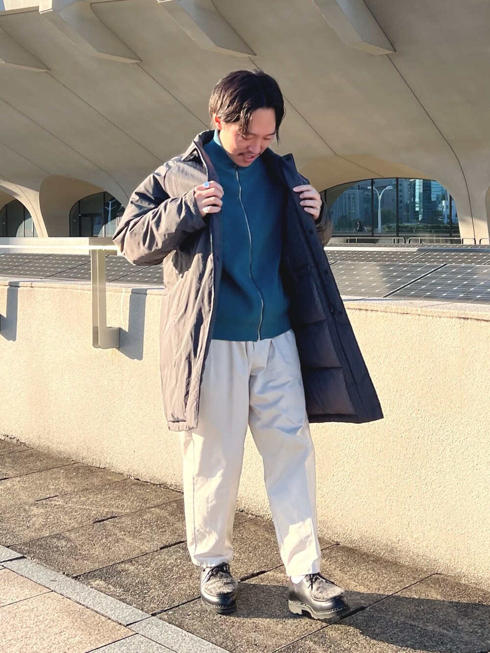 グレー系のダウンジャケット/コート、ブルー系のニット/セーター、ブラック系のその他シューズを着用したメンズの秋コーディネートの5枚目の写真