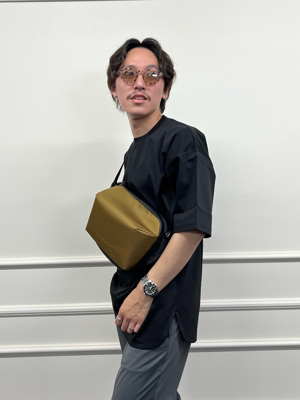 ブラック系のTシャツ/カットソー、グリーン系のショルダーバッグ、グレー系のその他パンツを着用したメンズの春コーディネートの8枚目の写真