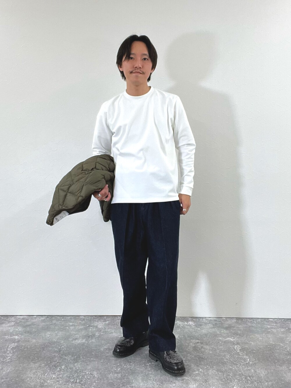 グリーン系のダウンジャケット/コート、ホワイト系のスウェット、ブラック系のブーツを着用したメンズの秋コーディネートの3枚目の写真