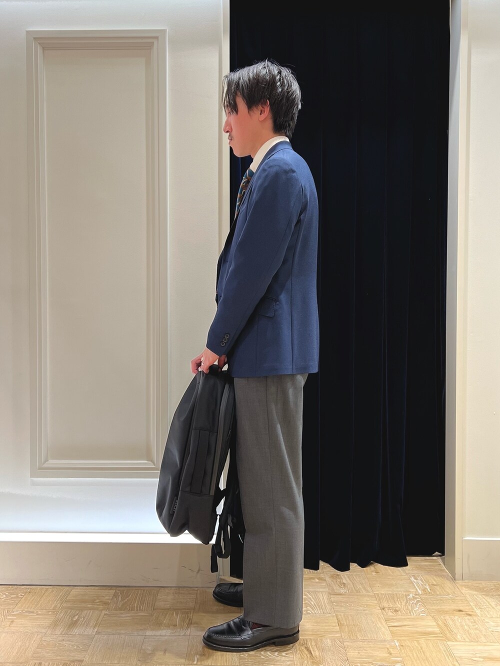 ブルー系のネクタイ、ブルー系のテーラードジャケット、ブラック系のバックパック/リュックを着用したメンズの春コーディネートの5枚目の写真