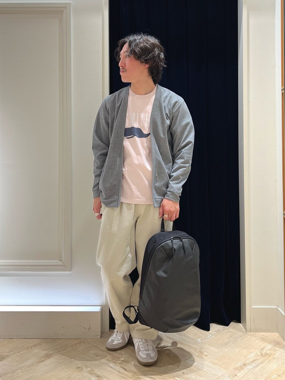 グレー系のカーディガン/ボレロ、ピンク系のTシャツ/カットソー、ブラック系のバックパック/リュックを着用したメンズの春コーディネートの2枚目の写真