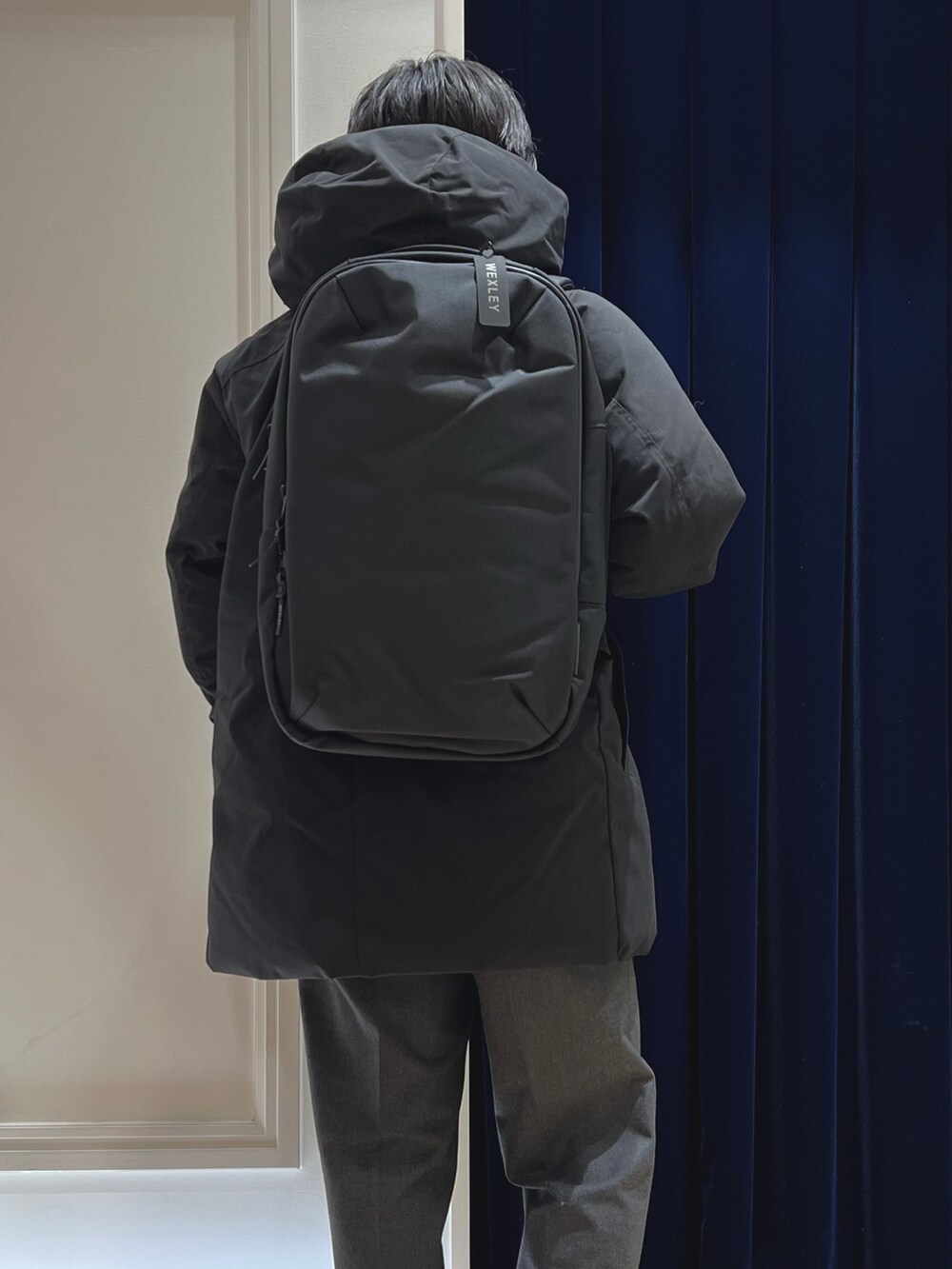 ブラック系のダウンジャケット/コート、グレー系のカーディガン/ボレロ、ブラック系のバックパック/リュックを着用したメンズの冬コーディネートの9枚目の写真