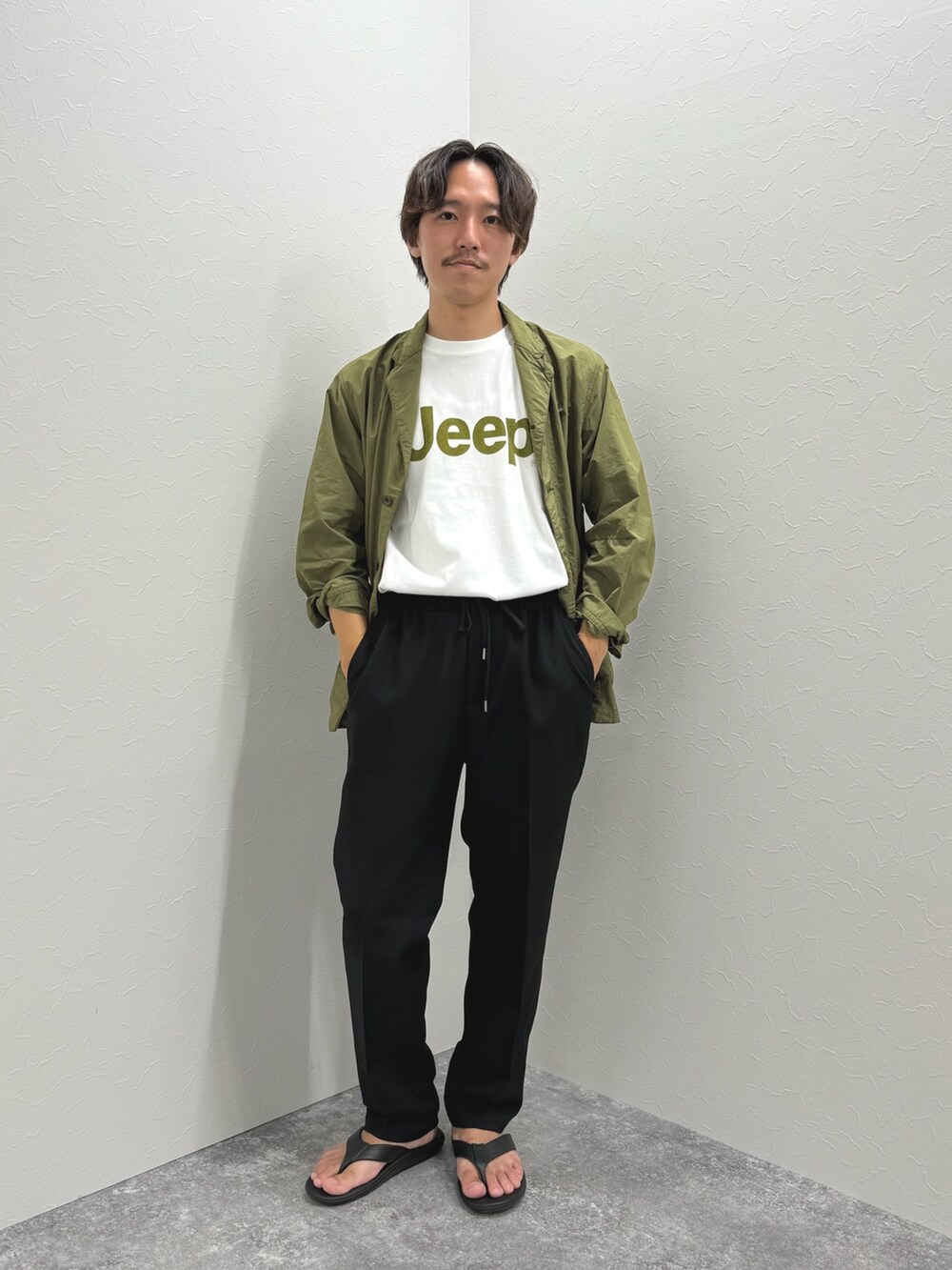 ホワイト系のTシャツ/カットソー、グリーン系のミリタリージャケット、ブラック系のその他パンツを着用したメンズの夏コーディネートの2枚目の写真