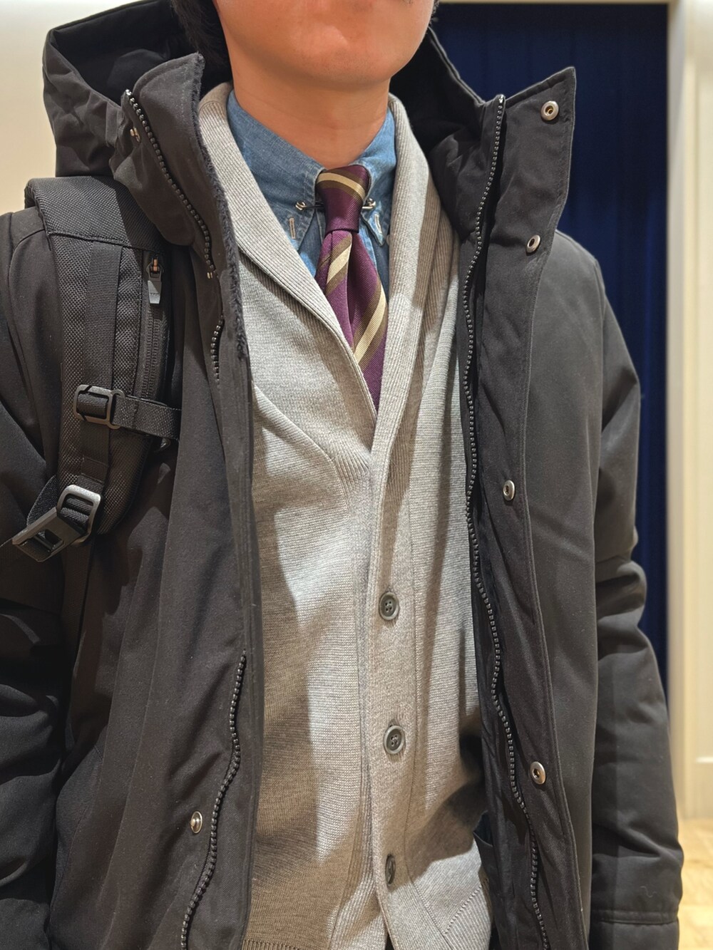 ブラック系のダウンジャケット/コート、グレー系のカーディガン/ボレロ、ブラック系のバックパック/リュックを着用したメンズの冬コーディネートの8枚目の写真