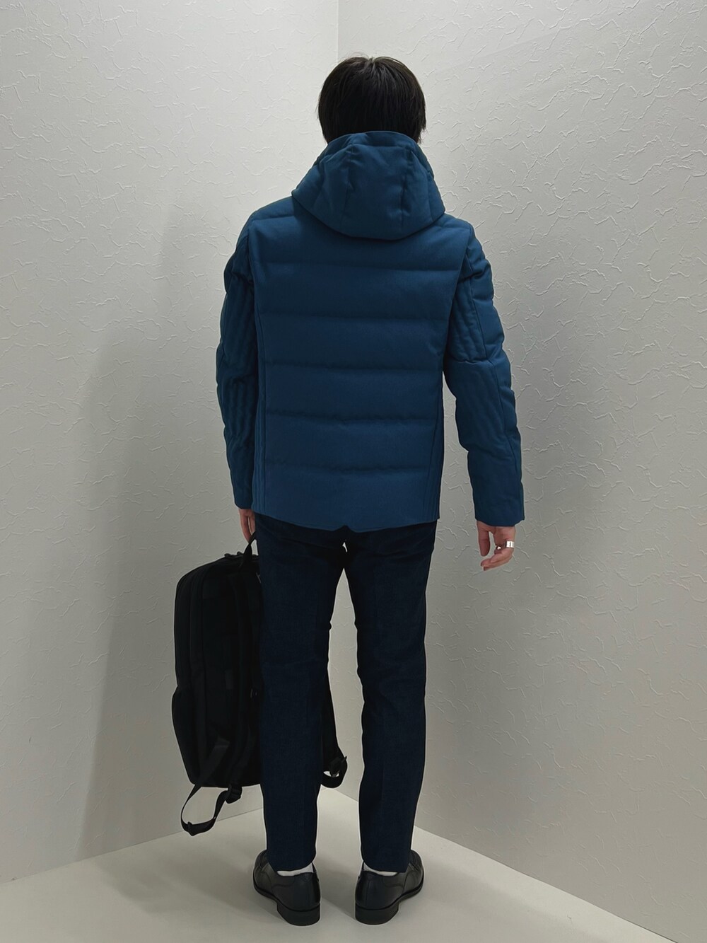 パープル系のニット/セーター、ブルー系のダウンジャケット/コート、ブラック系のバックパック/リュックを着用したメンズの秋コーディネートの5枚目の写真