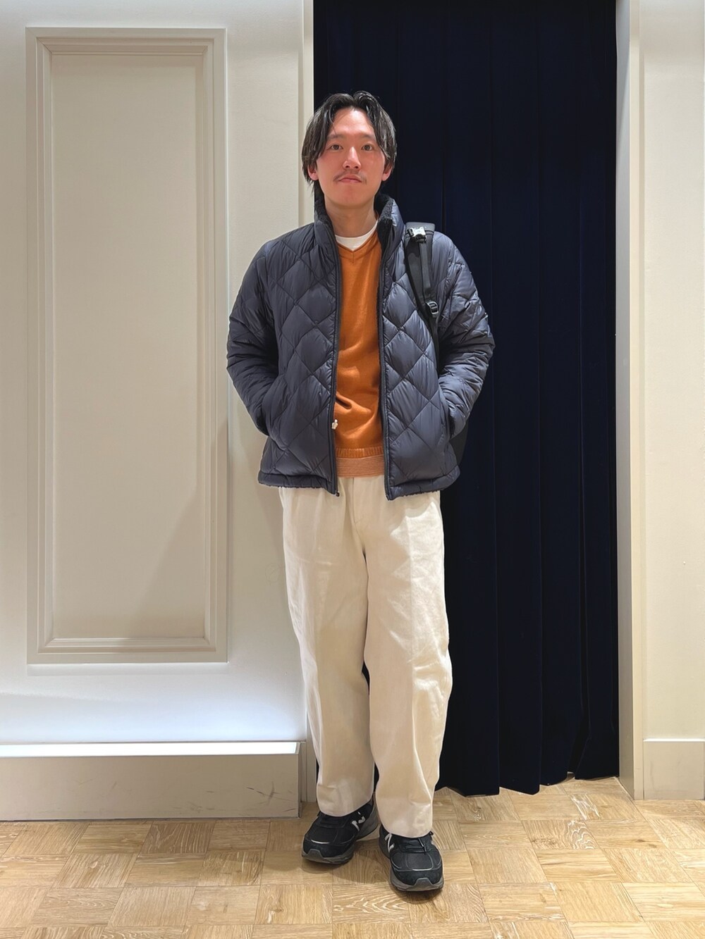 ブルー系のダウンジャケット/コート、イエロー系のニット/セーター、ブラック系のバックパック/リュックを着用したメンズの冬コーディネートの2枚目の写真