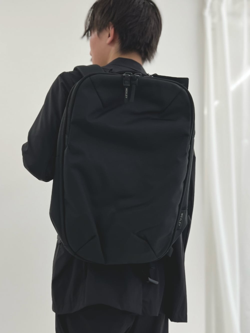 ブラック系のバックパック/リュック、ブルー系のテーラードジャケット、ブルー系のその他パンツを着用したメンズの夏コーディネートの6枚目の写真