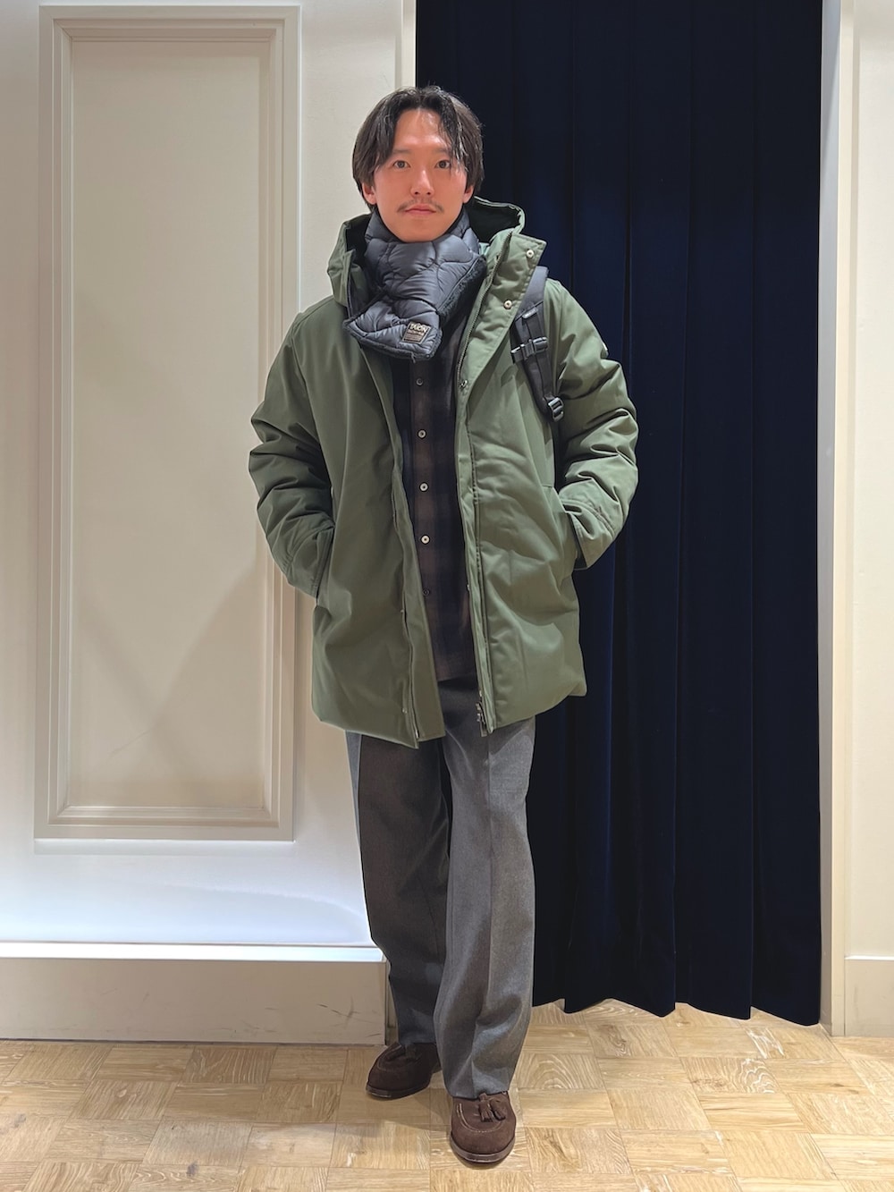 グリーン系のシャツ/ブラウス、ブラック系のバックパック/リュック、グリーン系のダウンジャケット/コートを着用したメンズの冬コーディネートの4枚目の写真