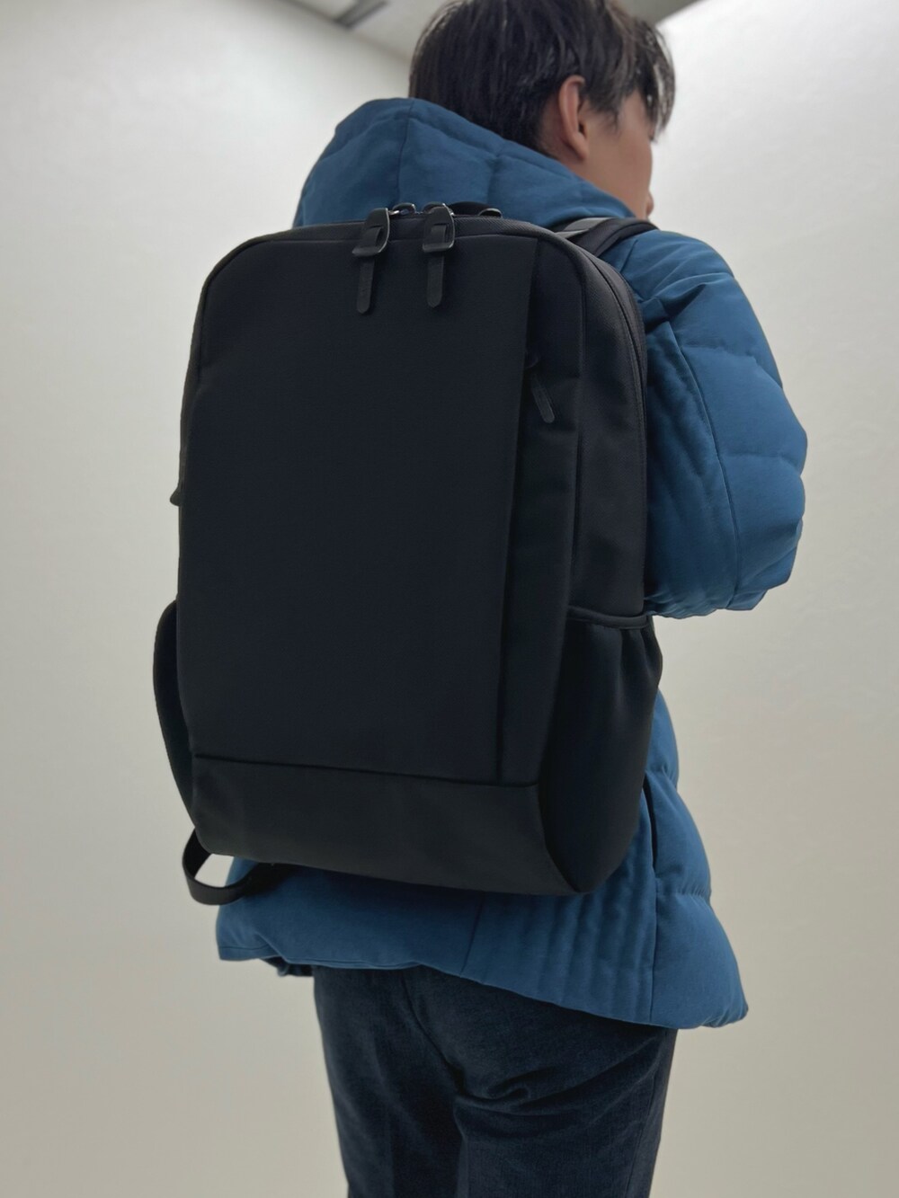 パープル系のニット/セーター、ブルー系のダウンジャケット/コート、ブラック系のバックパック/リュックを着用したメンズの秋コーディネートの7枚目の写真