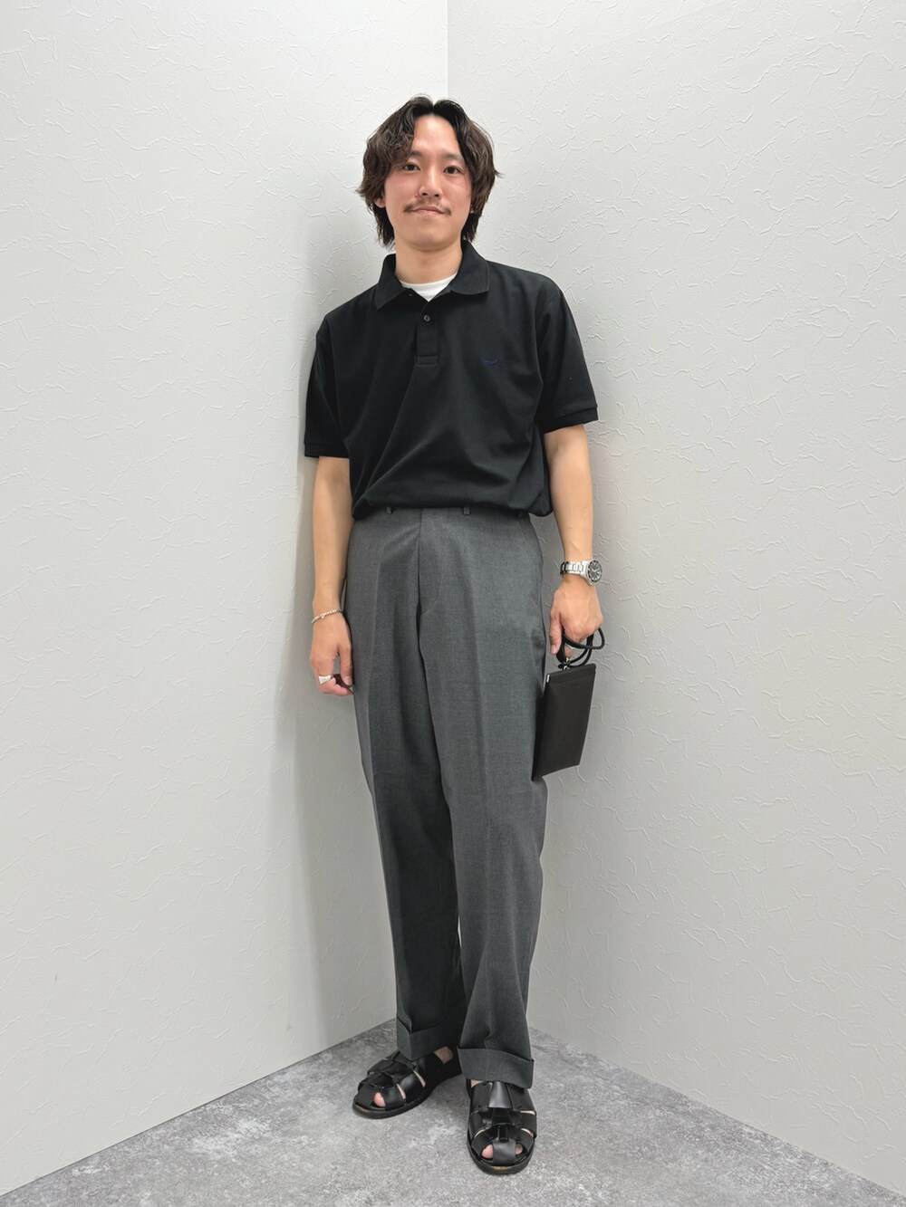 ブラック系のポロシャツ、ブラック系のショルダーバッグ、ブラック系のサンダルを着用したメンズの春コーディネートの2枚目の写真