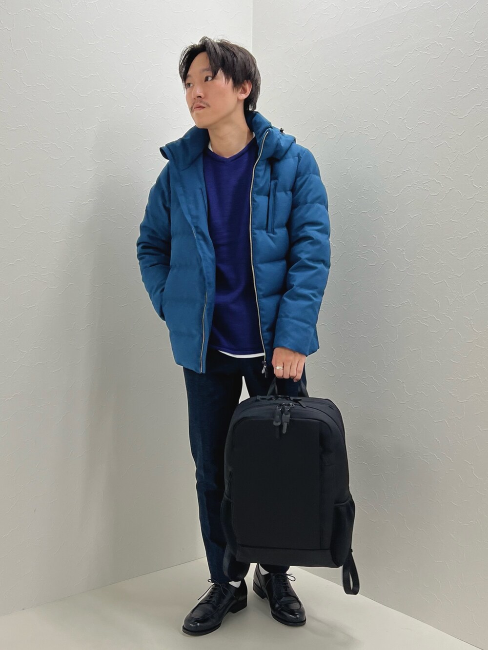 パープル系のニット/セーター、ブルー系のダウンジャケット/コート、ブラック系のバックパック/リュックを着用したメンズの秋コーディネートの2枚目の写真