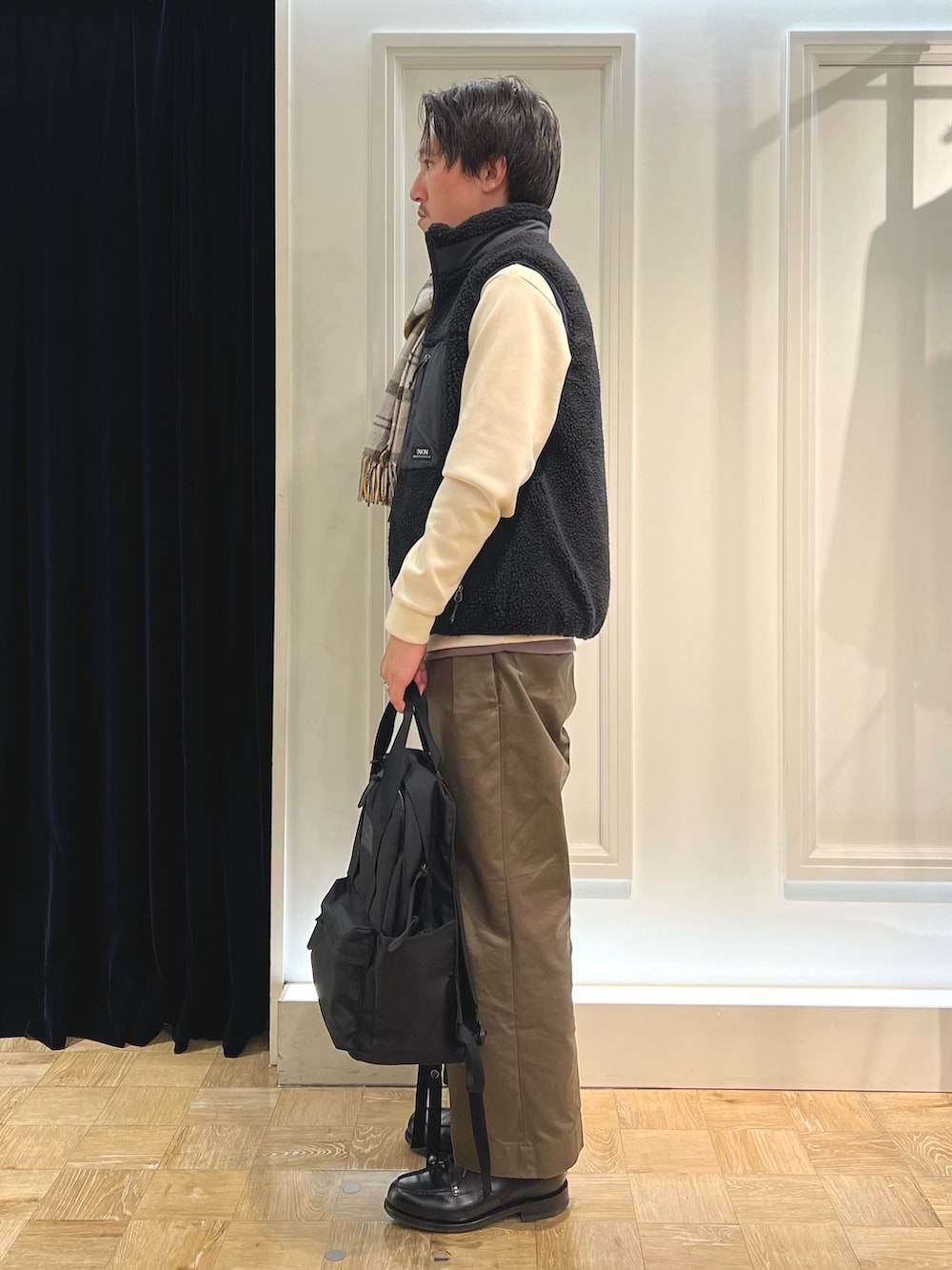 ブラック系のダウンベスト、ホワイト系のTシャツ/カットソー、ブラック系のバックパック/リュックを着用したメンズの秋コーディネートの3枚目の写真