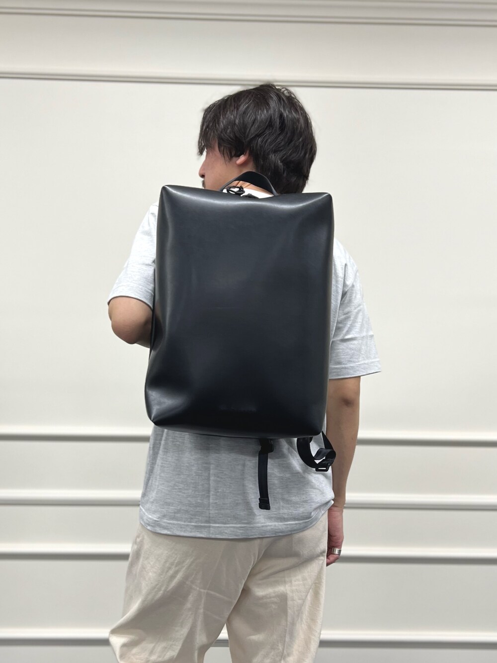 グレー系のTシャツ/カットソー、ブラック系のバックパック/リュック、ホワイト系のデニムパンツを着用したメンズの冬コーディネートの8枚目の写真