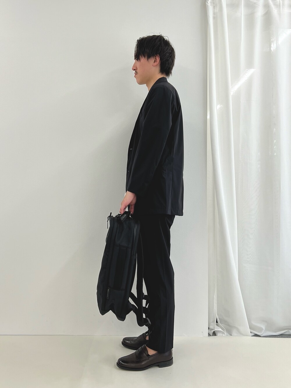 ブラック系のバックパック/リュック、ブルー系のテーラードジャケット、ブルー系のその他パンツを着用したメンズの夏コーディネートの4枚目の写真